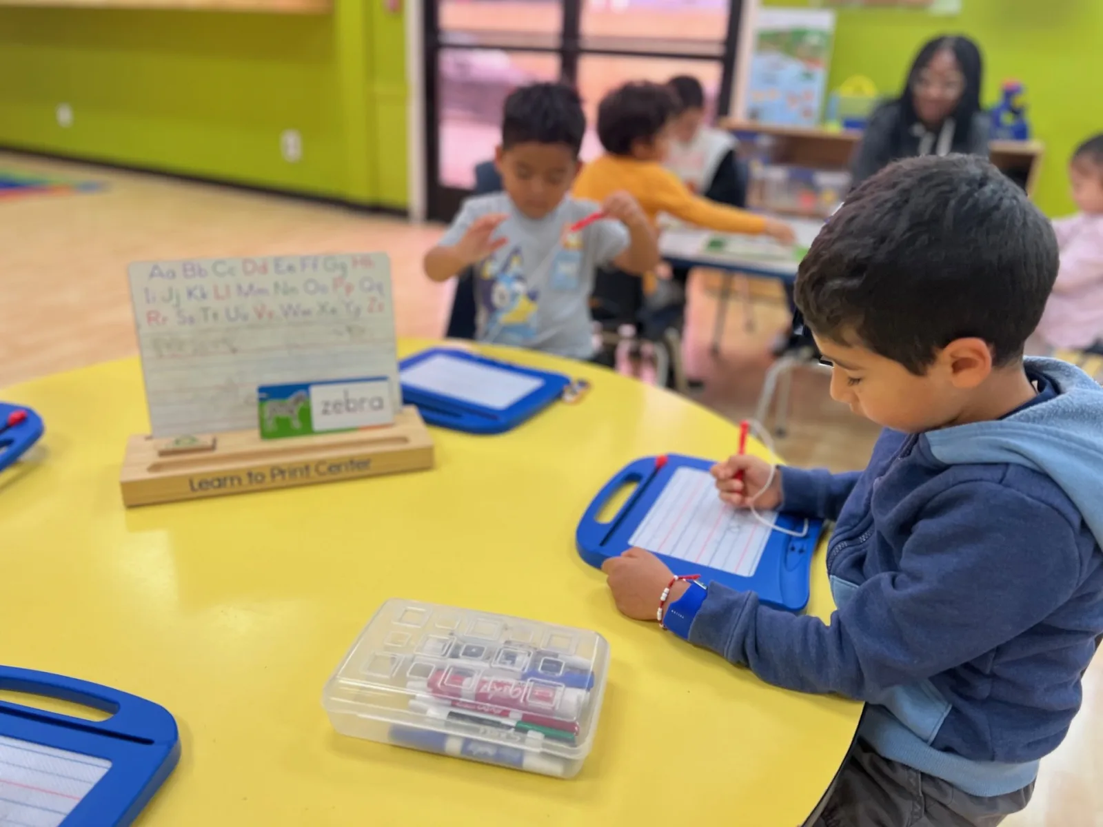Toddler painting at an easel in Fullerton, a vertical-surface activity that builds wrist extension and proximal stability for later handwriting