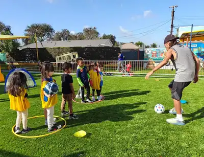 Preschool children learning teamwork and athletic skills during an organized soccer enrichment activity at Kids Adventure Learning Center