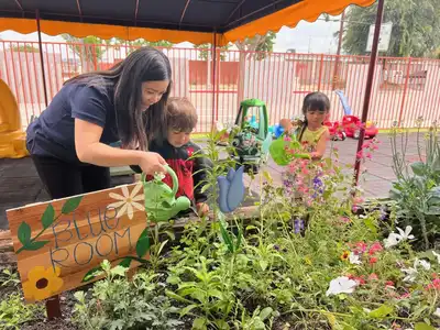 Children tending the on-site learning garden at Kids Adventure Learning Center, part of a fresh, healthy nutrition program with hot meals cooked on-site daily
