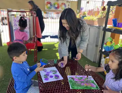 Teacher guiding a young child through a hands-on art and creative expression project in a Montessori-inspired preschool classroom