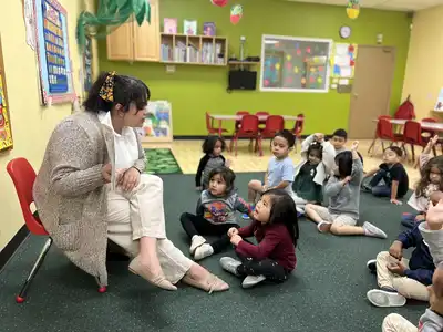 Preschool educator providing individualized attention and hands-on learning support to young children in a caring classroom environment